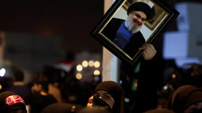 صورة تظهر امرأة ترفع صورة للأمين العام لحزب الله حسن نصر الله خلال مظاهرة في العاصمة العراقية بغداد