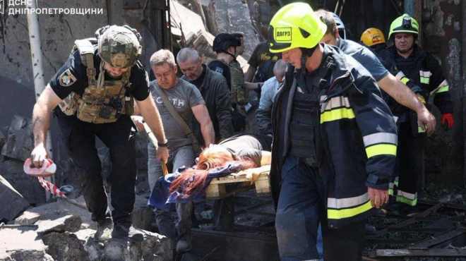 Спасатели несут на носилках пострадавшего при российском ударе