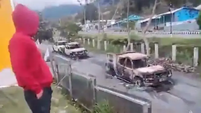 Seorang warga menyaksikan mobil yang dibakar warga di Puncak Jaya, Papua.