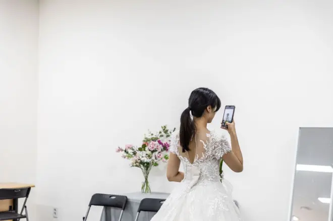 웨딩드레스를 입고 휴대폰을 보고 있는 신부의 뒷모습
