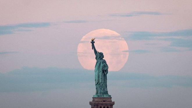 在美国纽约的自由女神像对照下，月亮特别大