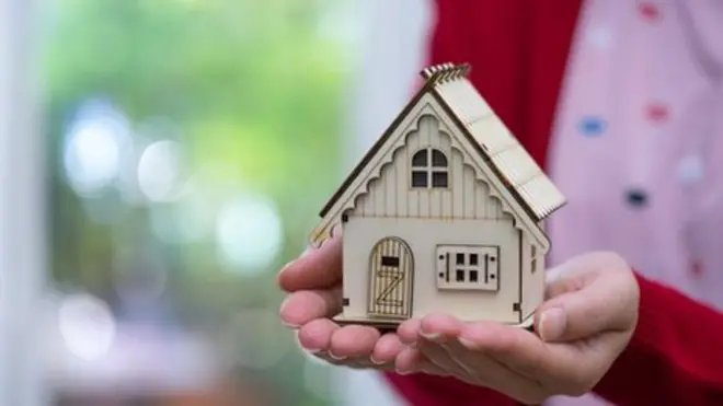 امرأة تحمل بيت صغير