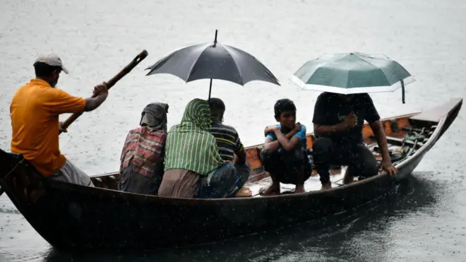 ছাতা মাথায় নৌকায় নদী পারাপার।