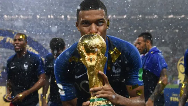 اللاعب الفرنسي امبابي وهو يحتفل بالفوز حاملا الكأس. امبابي هو من أصول جزائرية/كاميرونية وتم تتويجه بجائزة أفضل لاعب شاب في البطولة.