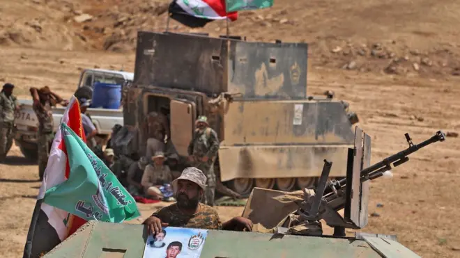 مقاتلون من قوات الحشد الشعبي في العراق يتقدمون في ضواحي مدينة تلعفر حاملين بعض الأعلام والصور