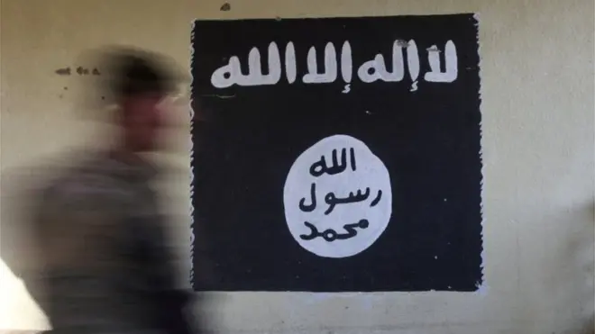 A member of the Iraqi rapid response forces walks past a wall painted with the black flag commonly used by Islamic State militants, at a hospital damaged by clashes during a battle between Iraqi forces and Islamic State militants in the Wahda district of Mosul, Iraq, on 8 January 2017