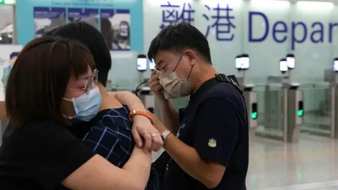 在香港机场的离港闸前，两人相拥，另外一人以纸巾抹眼泪。