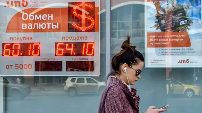 Una mujer pasa frente a un banco que muestra el cambio del rublo