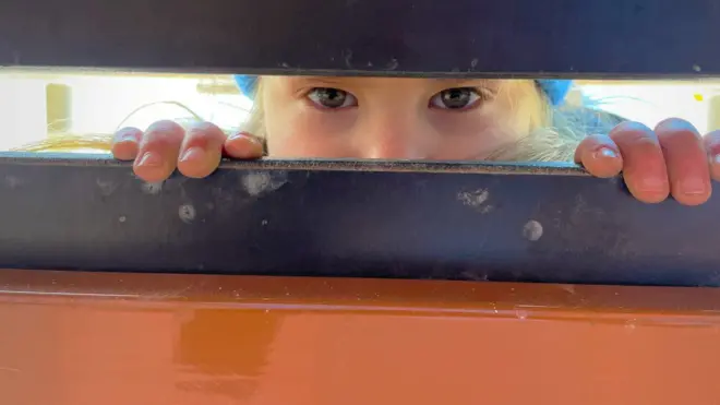 Ksusha looks through a door