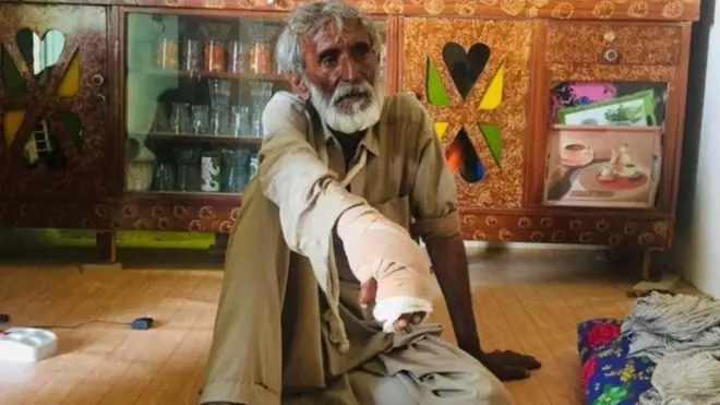 Siahouk, with his hand bandaged, sitting on the floor of his home