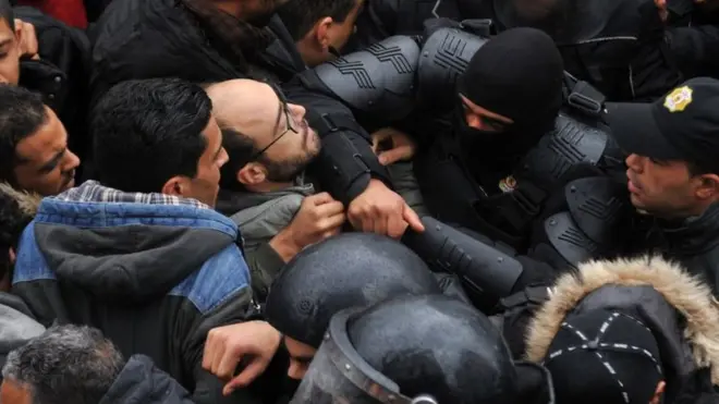 Une importante foule de manifestants contenue par des agents des forces de l'ordre.