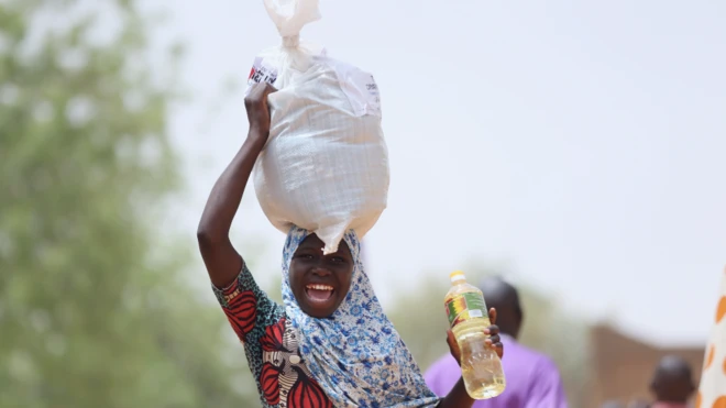 A smiling woman carrying aid supplies in Niamey, Niger - Wednesday 23 March 2022