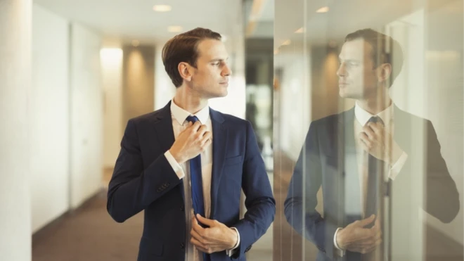 รูปชายใส่สูทมองเงาตัวเอง