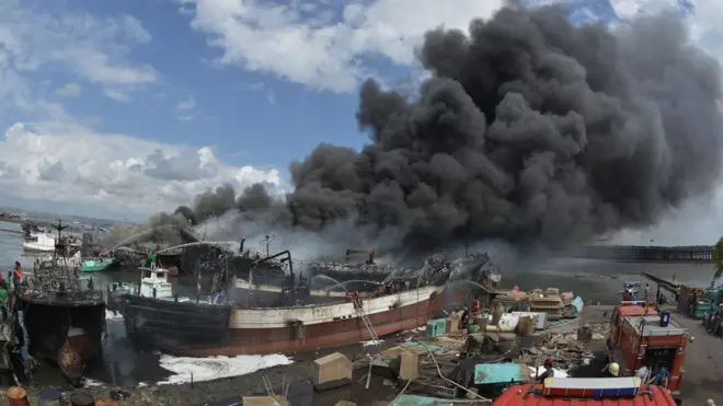 Petugas pemadam kebakaran dan warga berusaha memadamkan api yang membakar kapal ikan di Pelabuhan Benoa, Denpasar, Bali, Senin (9/7).