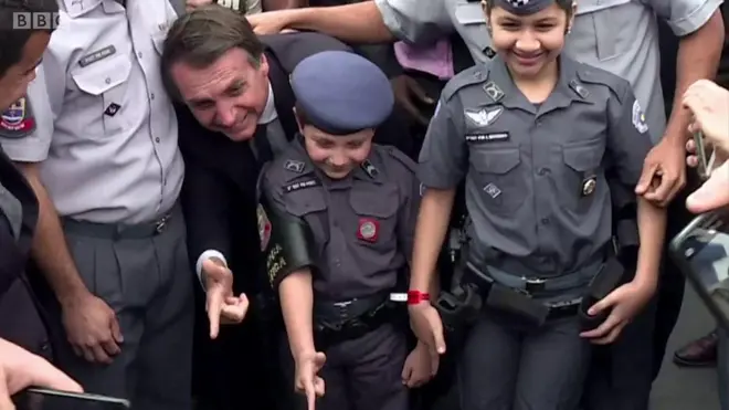 Žair Bolnosaro savija prste u obliku pištolja sa decom obučenom u policijske uniforme