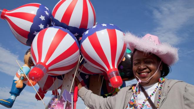 Una mujer sostiene globos con la bandera de Estados Unidos.