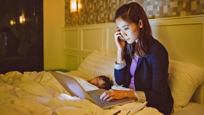 Una persona usando su laptop en mitad de la noche en la cama