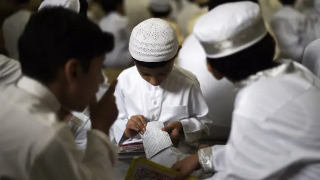 Bocah-bocah Muslim di Bahrain membaca Al-Quran, kitab suci agama Islam, pada bulan Ramadan.