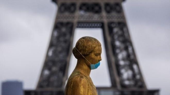 A golden statue of the Trocadero esplanade in Paris wearing a face mask