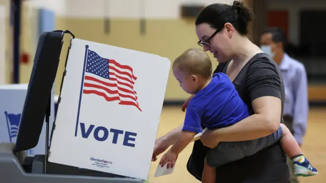 A woman carrying a child casts her vote in US primaries in Virginia