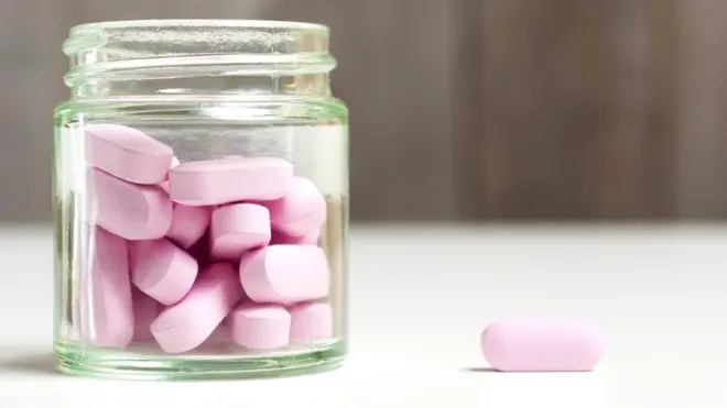 Un frasco y píldoras rosas