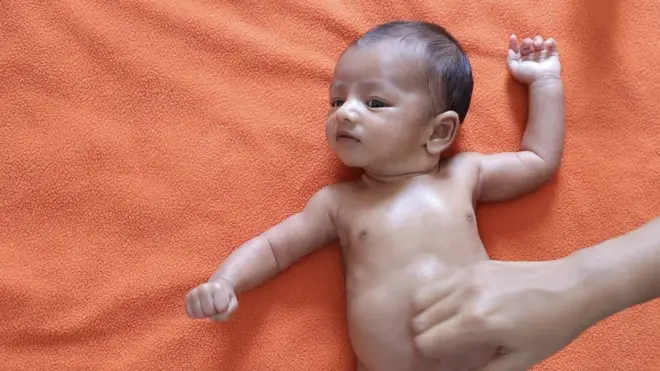 A baby having its stomach massaged