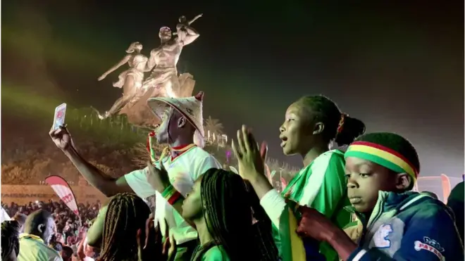 Supporters du Sénégal arborant les couleurs nationales au pied du monument de la renaissance africaine