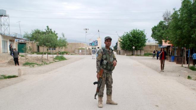 Афганский военный стоит у ворот базы, на которую напали талибы
