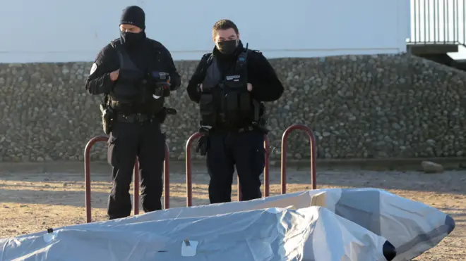 Police officers stand next to a boat after a rescue operation of migrants who tried to cross the Channel, in Berck, France January 14, 2022