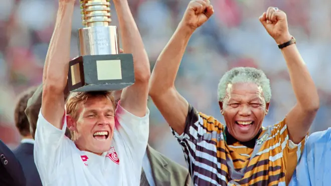 Neil Tovey celebrates by lifting the Afcon trophy of 1996 alongside Nelson Mandela