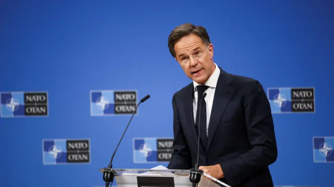 Mark Rutte Nato logolu bir kürsüde açıklama yaparken. 