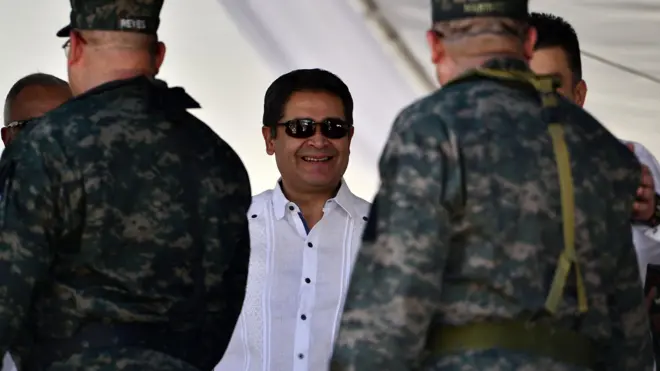 Juan Orlando Hernández sonríe rodeado de militares siendo presidente de Honduras, en 2019