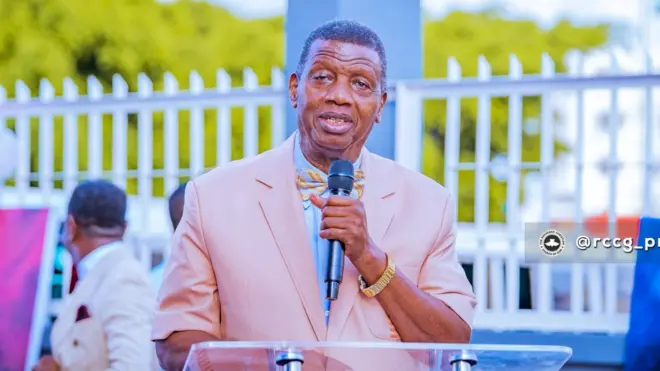 RCCG General Overseer Pastor E.A. Adeboye wear brown suit and hold microphone