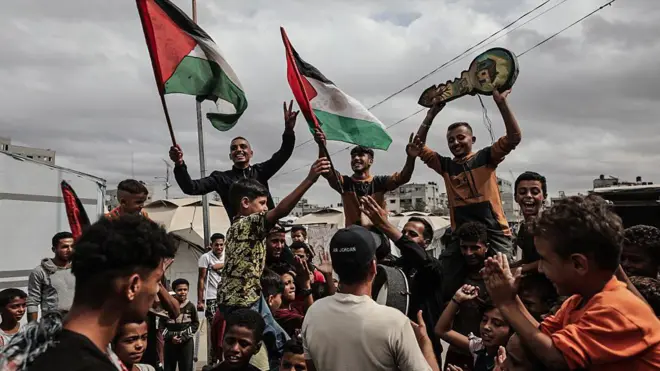 غزيون يرفعون الأعلام الفلسطينية ويحتلفون بإبرام المرحلة الأولى من وقف إطلاق النار بين إسرائيل وحماس