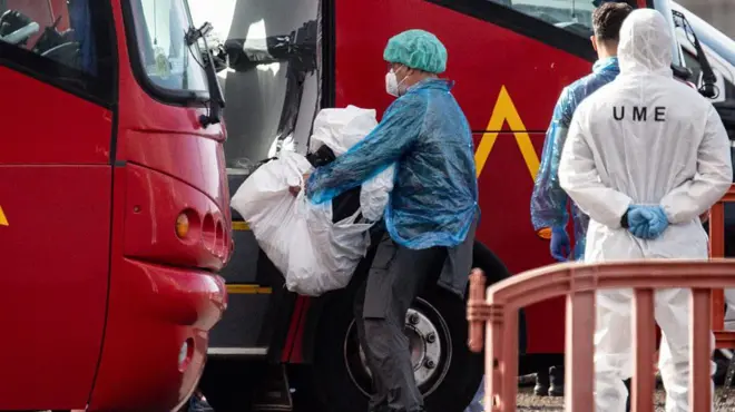 Otu onye njem na-ebu ngwongwo ya n'ime akpa plastik gaa na bọs na-eche mgbe a kpụpụrụ ya n’ụgbọmmiri MV Hondius mgbe ọ kwụsịrị n'ọdọụgbọmmiri Granadilla n’ụbọchị Sọnde Mee 10, 2026 na Tenerife dị nso n'agwaetiti Canary nke Spen.