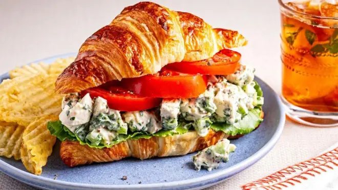 قطعة كرواسان في طبق محشوة بالجبنة والطماطم والخس