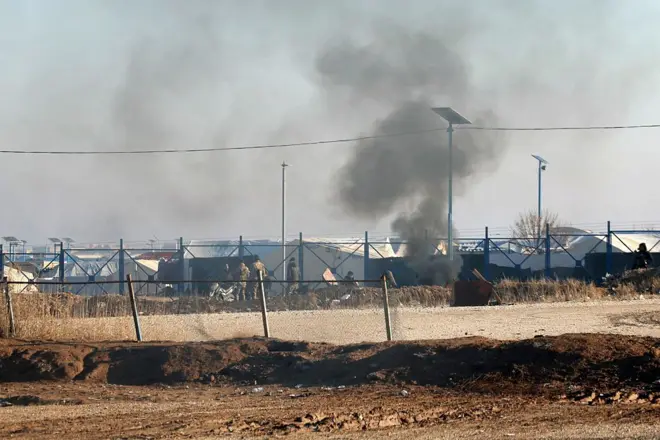 Suriye güvenlik güçleri El Hol Kampı'nda görülüyor. Önlerinde teller, arkalarında çadırlar var. Duman çıkıyor. (21 Ocak 2026)