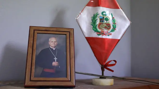 Imagem mostra foto de Roberto Prevost em um porta-retrato ao lado de uma bandeira do Peru