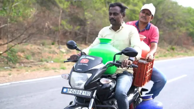 బైకుపై నీళ్లు తీసుకెళ్తున్న వ్యక్తులు
