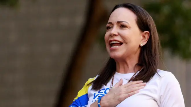 ヴェネズエラ国旗をあしらったTシャツを着たマチャド氏が胸に右手をあてて、集まった人たちに呼び掛けている。茶色いまっすぐの髪を肩の下まで伸ばし、真珠のイヤリングを着けている