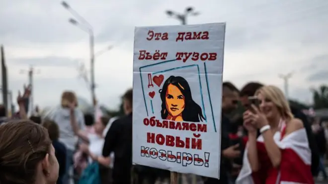 Митинг в Польше, один из участников несет плакат с портретом Светланы Тихановской на игральной карте с надписью «Эта дама бьет тузов, объявляем новый козырь»