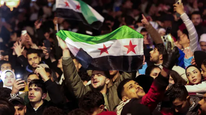 شاب يرفع العلم السوري الجديد