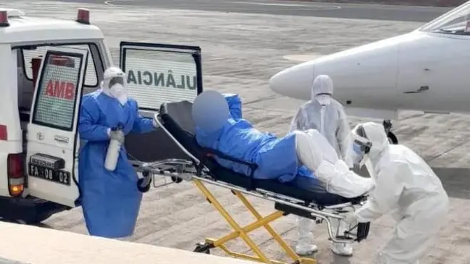 Sanitarios con equipamiento de protección especial suben a una persona en camilla a una ambulancia