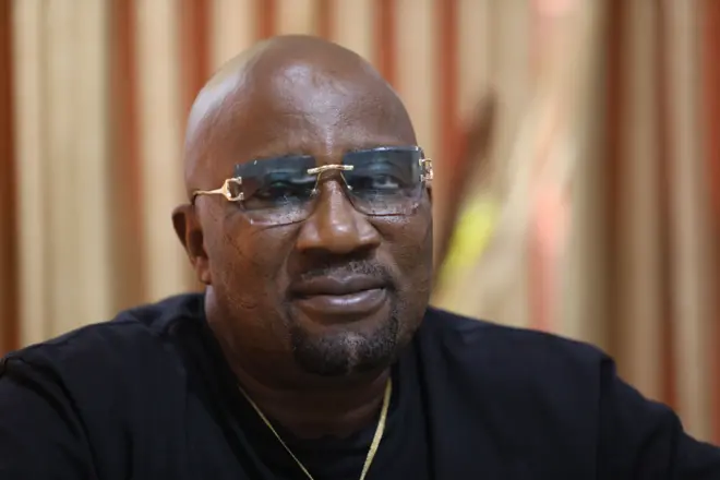 Baba Londoner - o wọ aṣọ dudu pẹlu igo loju rẹ ati ẹgba ọrun