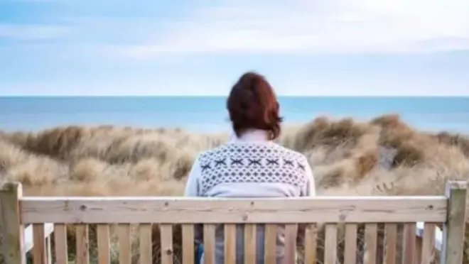 Persona sentada sola frente al mar