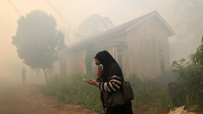 Seorang warga menutup hidung saat melintas di tengah asap akibat kebakaran hutan dan lahan (karhutla) yang mendekati permukiman di Kabupaten Kubu Raya, Kalimantan Barat, 5 Agustus 2026.