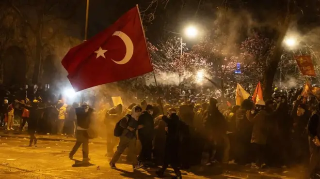 市長拘束に抗議するデモ隊。トルコの国旗が掲げられている