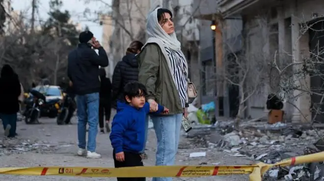 A woman with her child looks at the aftermath of an Israeli and the U.S. strike on a police station, 2 March 2026