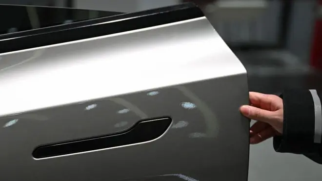 Женщина открывает дверь электромобиля Tesla Model Y в автосалоне в Пекине 3 февраля 2026 года.