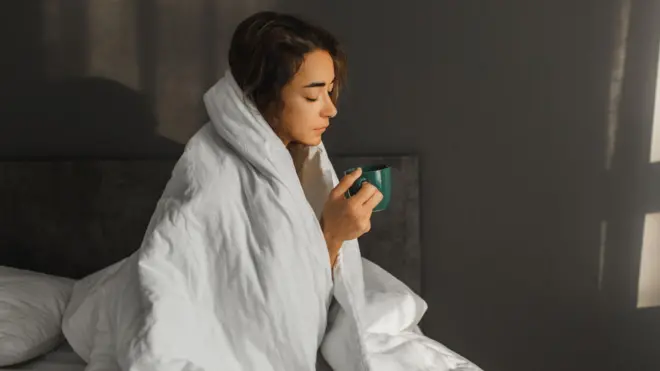 침대에서 차를 마시는 여성의 모습